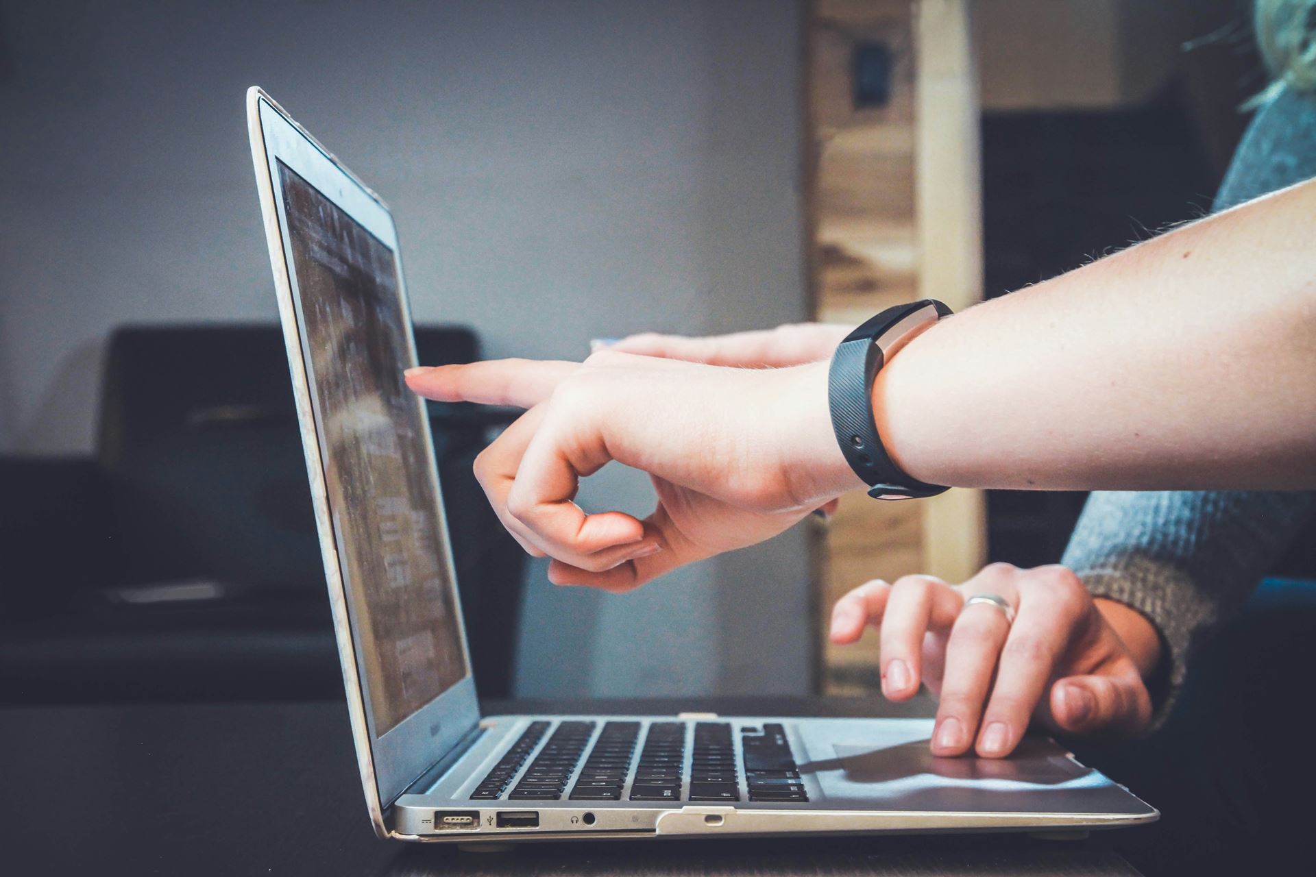 person pointing at a laptop